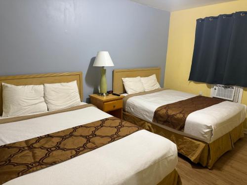 a hotel room with two beds and a lamp at Crown Inn in Fort Lauderdale