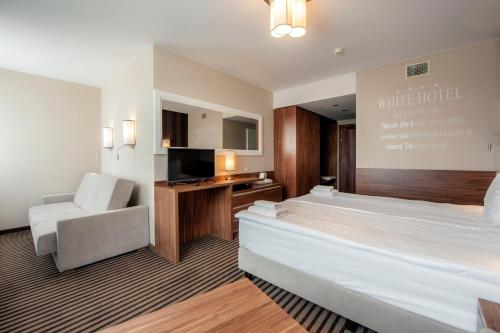 a hotel room with a bed and a chair at Hotel White in Krynica Morska
