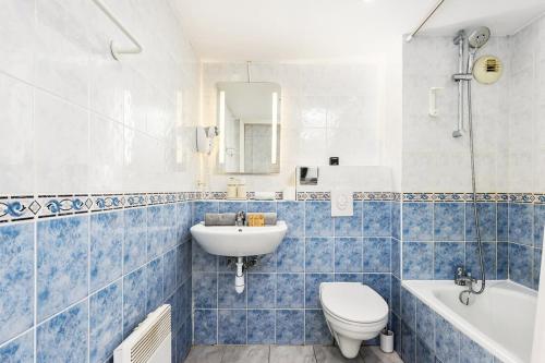 La salle de bains est pourvue de carrelage bleu, de toilettes et d'un lavabo. dans l'établissement Monte carlo riviera, à Beausoleil
