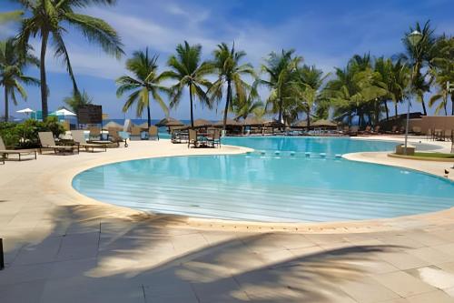 a large swimming pool with palm trees in a resort at BVG ixtapa in Ixtapa