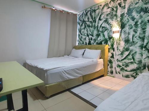 Hotel O Green Leaf Guest Lodge Kk في كوتا كينابالو: غرفة نوم صغيرة بها سرير وجدار أخضر