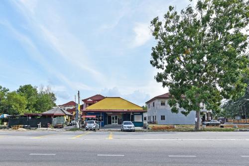 a building on the side of a street with a tree at Hotel O Zn Mix Homestay & Roomstay in Kampung Raja