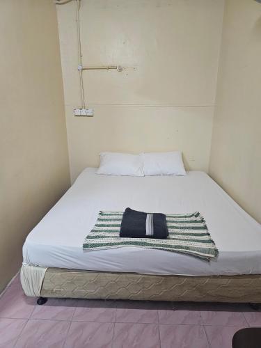 a bed with a black and white blanket on it at Hotel O Bintang Inns in Rawang