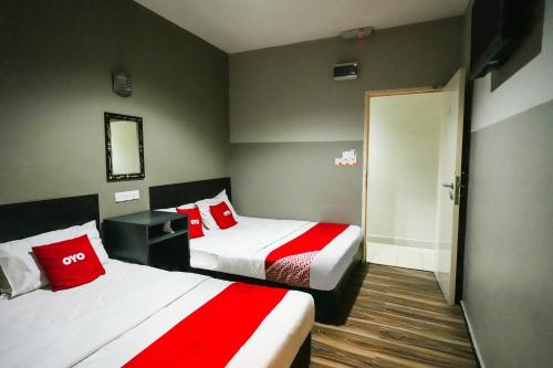 a hotel room with two beds with red pillows at Hotel O 365 Nice Stay in Miri