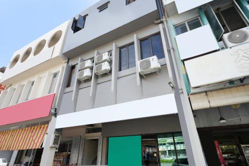 a white building with windows and a green door at Hotel O 365 Nice Stay in Miri