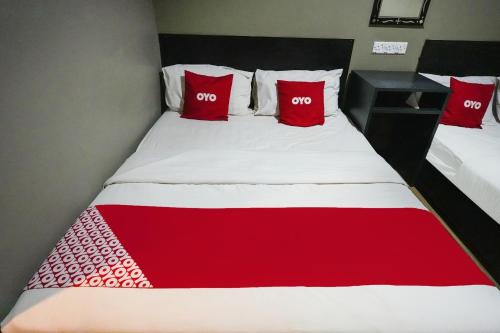 a red and white bed with two red pillows at Hotel O 365 Nice Stay in Miri