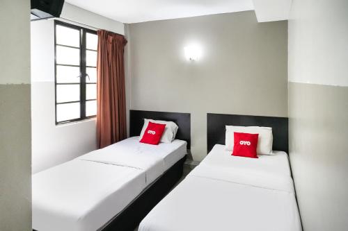 two beds in a room with red pillows at Hotel O 365 Nice Stay in Miri