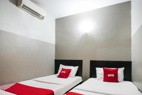two beds in a room with red pillows at Hotel O 365 Nice Stay in Miri