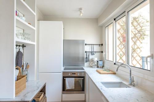 une cuisine avec un évier et une grande fenêtre dans l'établissement Appartement Invalides avec Terrasse, à Paris