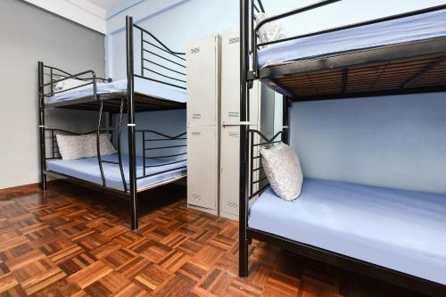 a room with two bunk beds and a wooden floor at Hotel O Kuantan Backpackers in Kuantan
