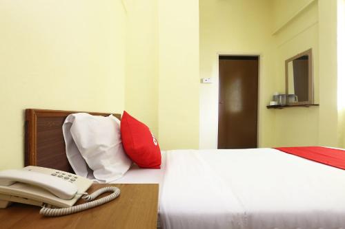a bed with a phone sitting on top of it at Hotel O Harmoni Hotel in Kota Bharu