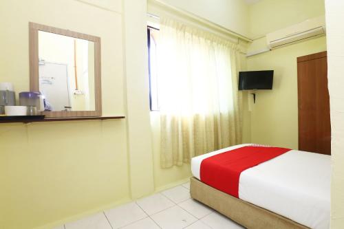 a bedroom with a bed with a red blanket and a window at Hotel O Harmoni Hotel in Kota Bharu