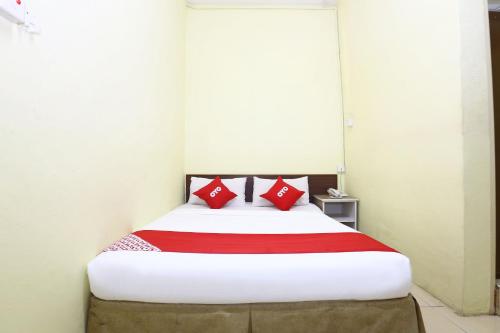 a bedroom with a bed with red pillows on it at Hotel O Harmoni Hotel in Kota Bharu