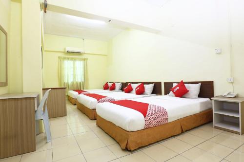 two beds in a hotel room with red pillows at Hotel O Harmoni Hotel in Kota Bharu