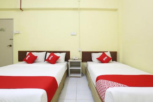 two beds in a room with red and white pillows at Hotel O Harmoni Hotel in Kota Bharu