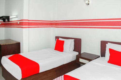 two beds in a room with red and white pillows at OYO 1173 Mandyrin Hotel in Sibu