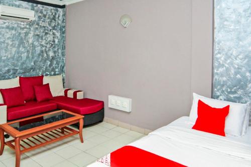 a living room with a red couch and a bed at OYO 1173 Mandyrin Hotel in Sibu