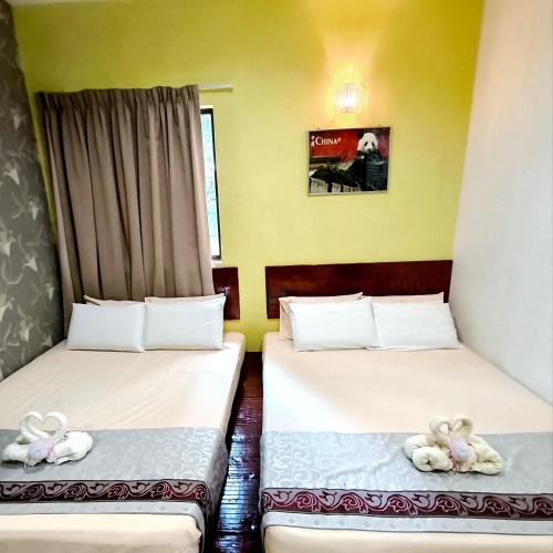 two beds with stuffed animals on them in a room at Hotel O Rumah Rehat Awana in Kampong Nanas