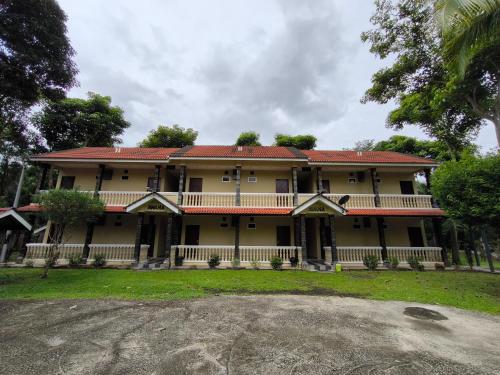 a large yellow house with a red roof at Hotel O Rumah Rehat Awana in Kampong Nanas