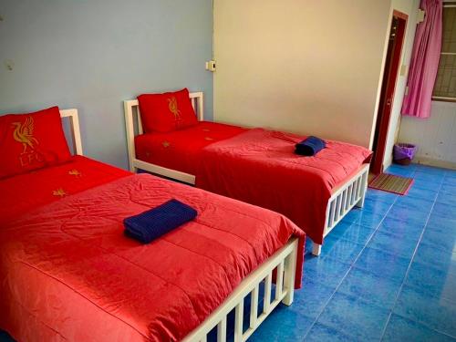 a room with three beds with red sheets and a chair at Baan Kenpoo Resort in Ban Na Pa