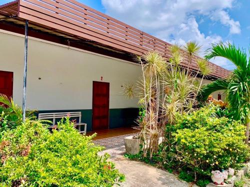 a white building with a red door and some plants at Baan Kenpoo Resort in Ban Na Pa