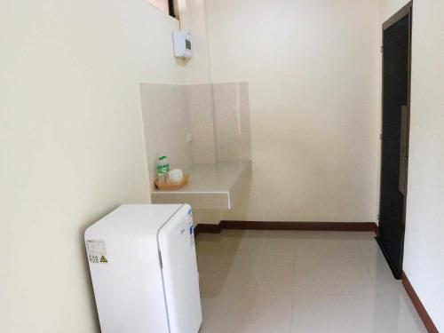 a small kitchen with a white refrigerator in a room at Capital O 75521 Sang Siri Apartment in Samut Songkhram