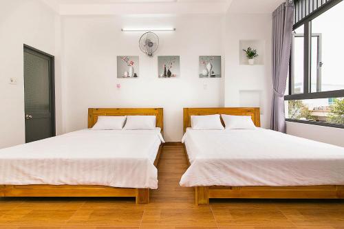 2 letti in una camera con pareti bianche e pavimenti in legno di SPOT ON 806 Net Viet Homestay a Da Nang