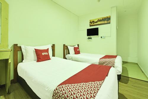 a hotel room with two beds and a tv at Hotel O Mini Indah in Kuala Terengganu