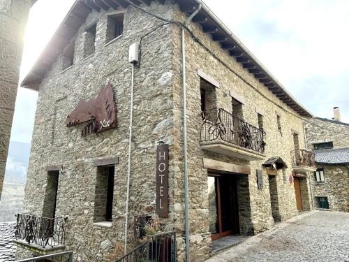 a stone building with a sign on the side of it at Hotel Rural L'Ortiga Blanca in Queralbs