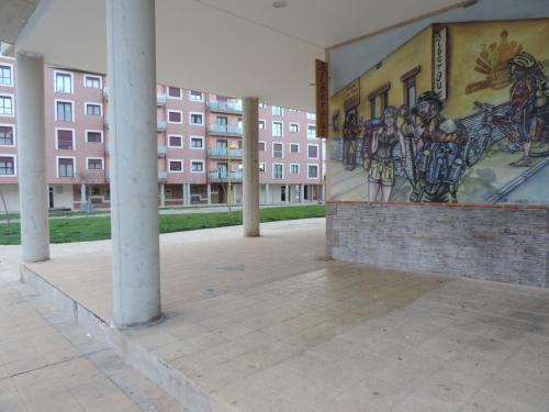 une fresque murale sur le côté d'un bâtiment avec colonnes dans l'établissement Albergue Santo Tomás de Canterbury, à León