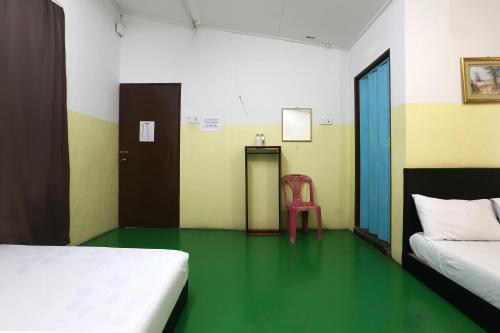 a room with two beds and a red chair in it at Hotel O Innap Kota Bharu in Kota Bharu