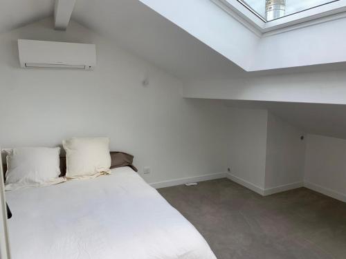 une chambre avec un lit blanc dans un grenier dans l'établissement Azkena, à Anglet