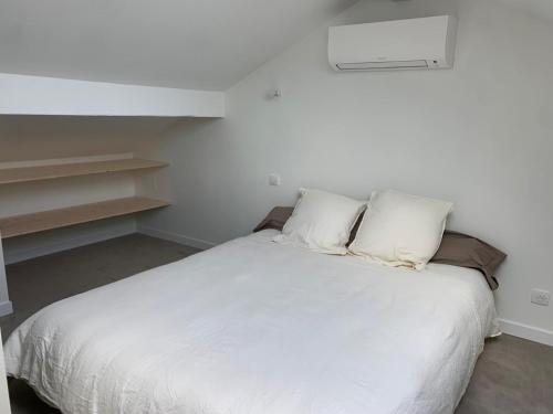 une chambre avec un lit avec des draps blancs et des oreillers dans l'établissement Azkena, à Anglet