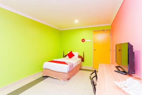 a green room with a bed and a tv at Hotel O Comfort in Ipoh