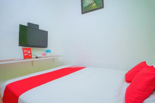 a bedroom with a bed with a tv on the wall at Hotel O V Stay Guesthouse in Ayer Itam