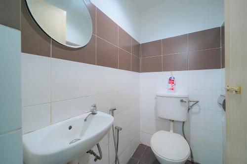 a bathroom with a sink and a toilet and a mirror at Hotel O V Stay Guesthouse in Ayer Itam