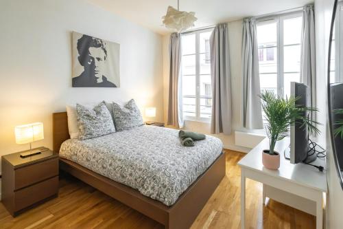 une chambre avec un lit, une télévision et des fenêtres dans l'établissement Elegant Duplex Montorgueil - 6 Guests, à Paris