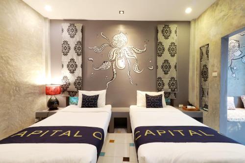 two beds in a room with a spider on the wall at Capital O 464 At Nata Chiangmai Chic Jungle in Mae Rim