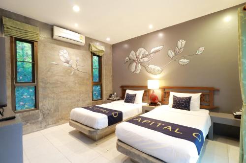 a hotel room with two beds and flowers on the wall at Capital O 464 At Nata Chiangmai Chic Jungle in Mae Rim