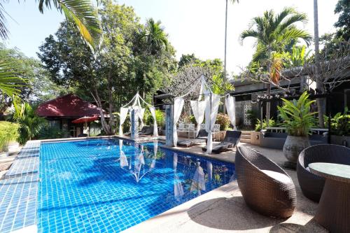 a swimming pool with chairs and a table and trees at Capital O 464 At Nata Chiangmai Chic Jungle in Mae Rim