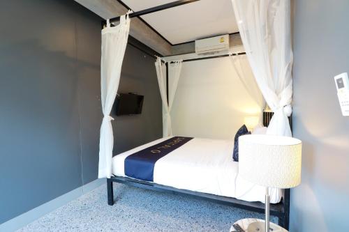 a small bedroom with a bed with white curtains at Capital O 464 At Nata Chiangmai Chic Jungle in Mae Rim