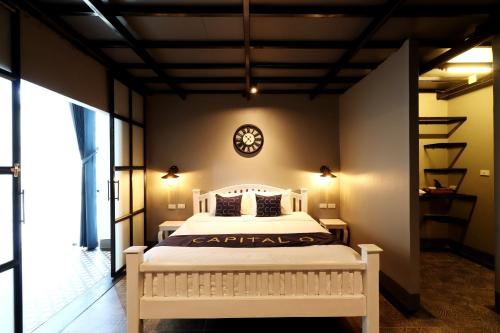 a bedroom with a white bed with a clock on the wall at Capital O 464 At Nata Chiangmai Chic Jungle in Mae Rim