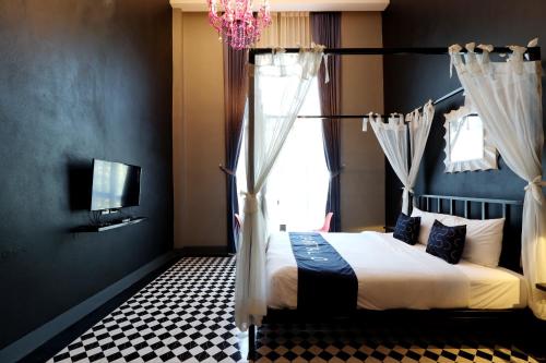 a bedroom with a bed with a chandelier and a window at Capital O 464 At Nata Chiangmai Chic Jungle in Mae Rim