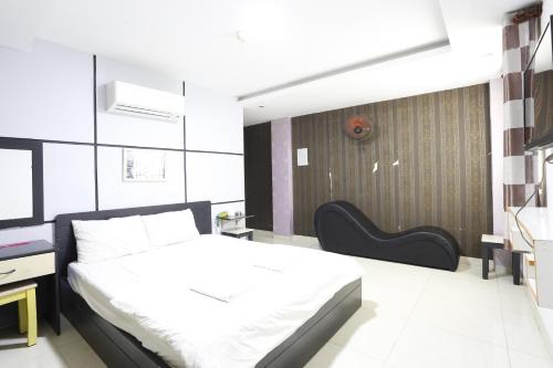 a bedroom with a white bed and a black chair at Avatar Hotel in Ho Chi Minh City