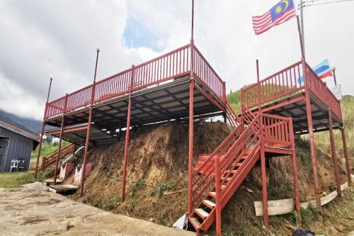 a red structure on top of a hill with a flag at Hotel O Sosodikon Inap Desa in Ranau