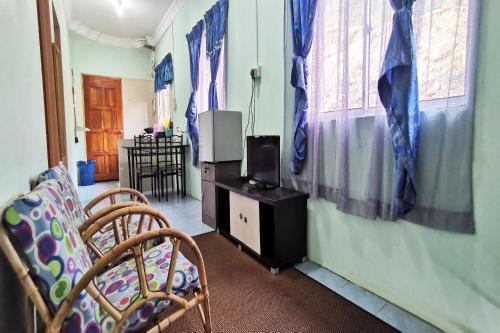 a living room with a tv and chairs and windows at Hotel O Sosodikon Inap Desa in Ranau
