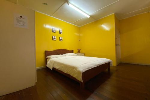 a bedroom with yellow walls and a large bed at Hotel O Rb Homestay & Farms in Kuching