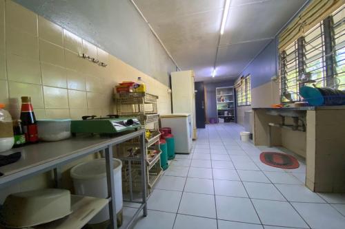 a large kitchen with a large white tiled floor at Hotel O Rb Homestay & Farms in Kuching