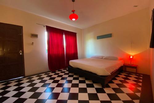 a bedroom with a bed with red curtains and a checkered floor at Hotel O Rb Homestay & Farms in Kuching