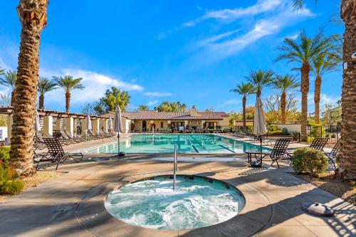 a swimming pool with chairs and palm trees at Spanish Walk Villa - PD condo near acrisure in Palm Desert